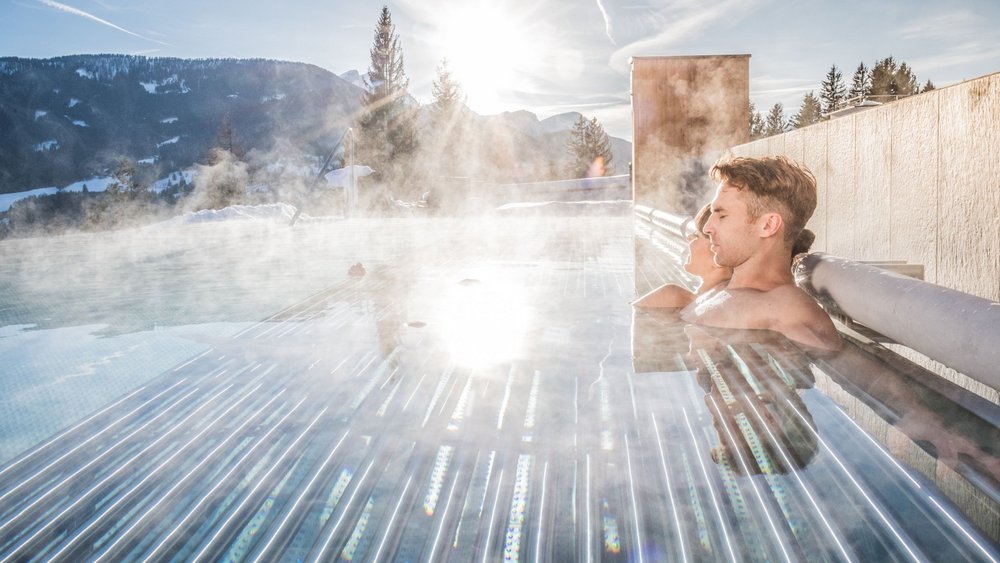 Le foto più belle dell’Alpen Tesitin Coppia rilassata in piscina esterna fumante con vista sulle montagne al sole
