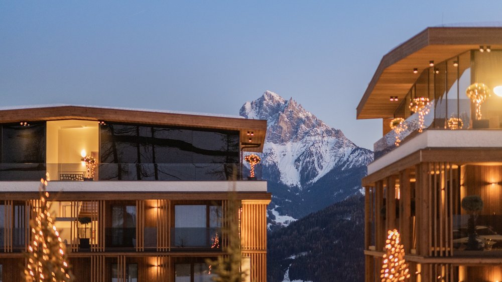 Le foto più belle dell’Alpen Tesitin Case moderne in legno con luci di Natale davanti a montagne innevate al tramonto
