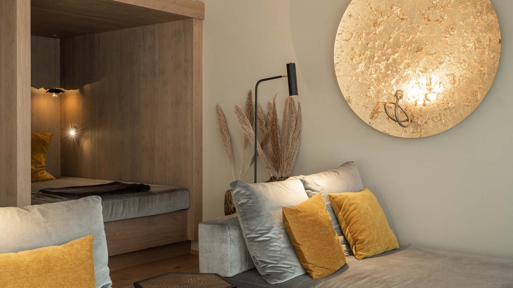 Le foto più belle dell’Alpen Tesitin Soggiorno moderno con divano grigio, cuscini gialli e decorazione murale dorata