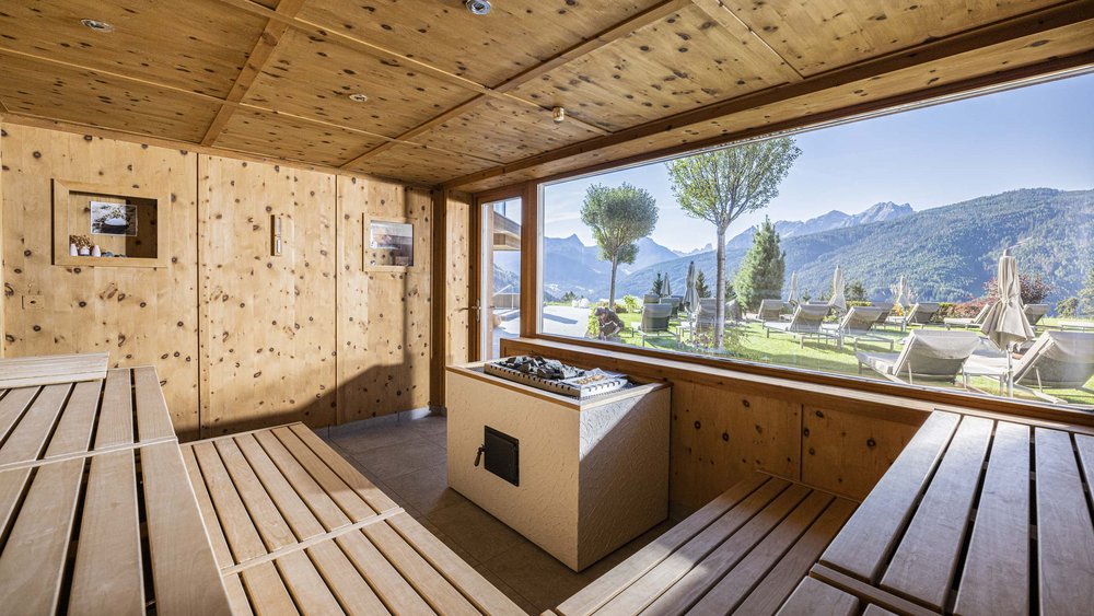 Le foto più belle dell’Alpen Tesitin Sauna con grande finestra con vista su montagne e giardino con lettini