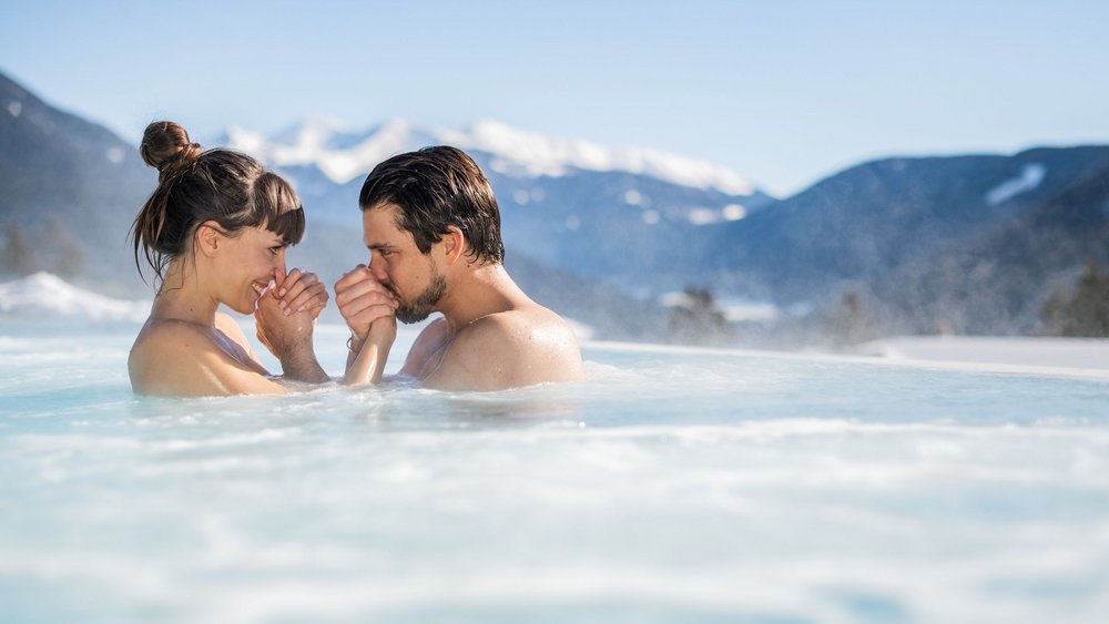 Le foto più belle dell’Alpen Tesitin Coppia rilassata in piscina all'aperto con montagne innevate sullo sfondo