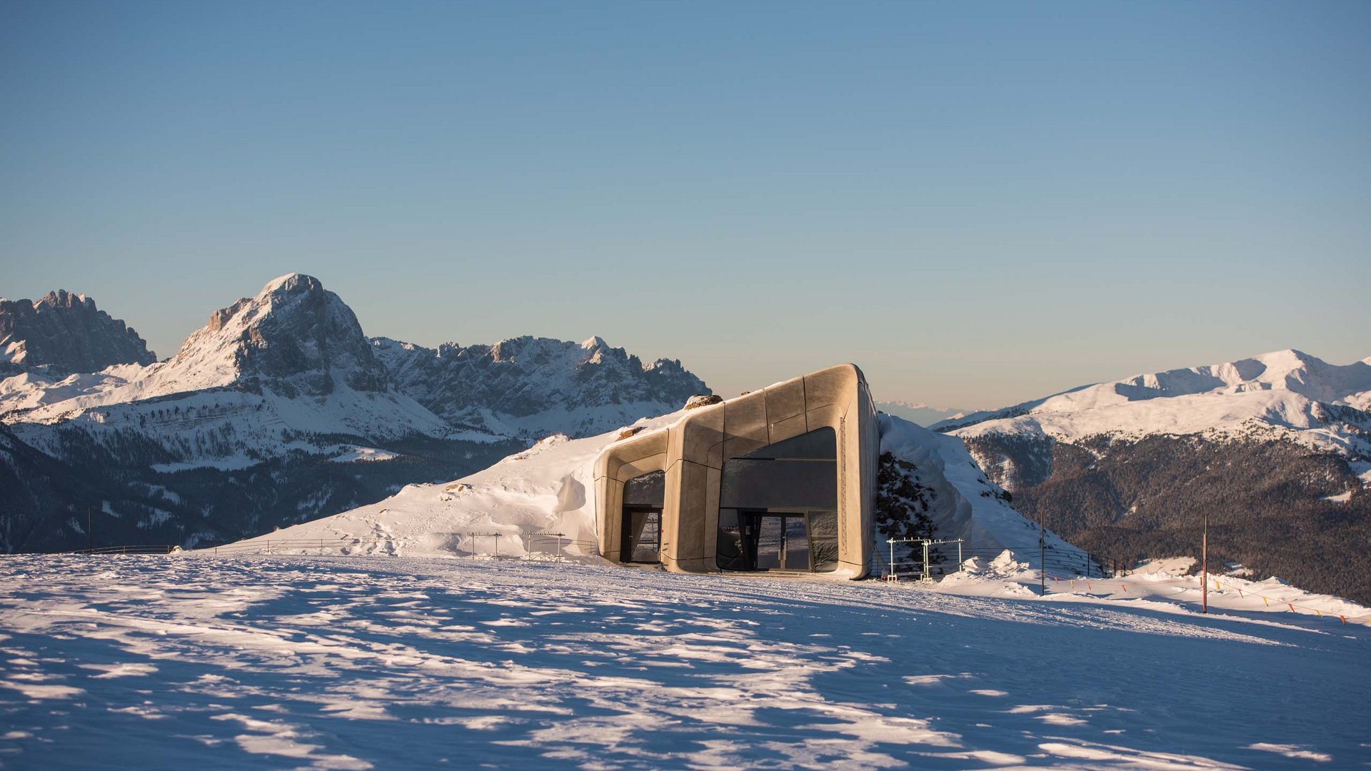 These attractions await you in Val Pusteria/Pustertal! Modern mountain hut in snowy landscape with mountains in background