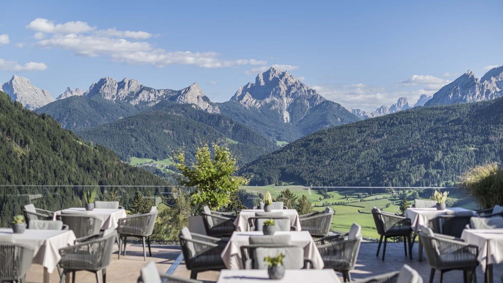 Le foto più belle dell’Alpen Tesitin Terrazza con tavoli vista su montagne verdeggianti e cielo blu