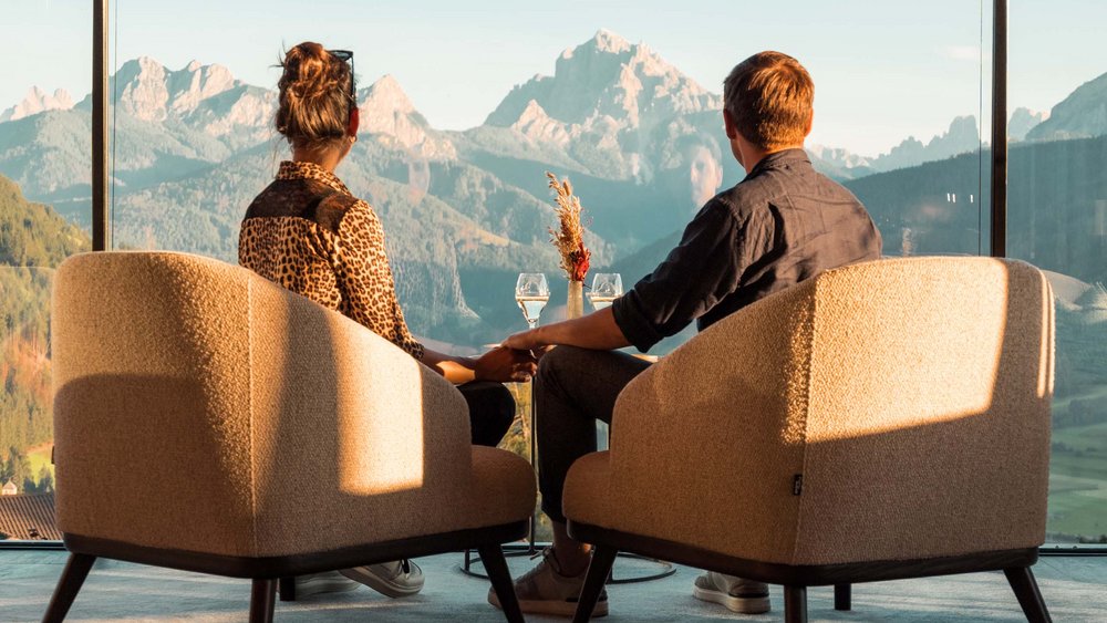 Le foto più belle dell’Alpen Tesitin Coppia seduta in poltrone che si tengono per mano con vista sulle montagne