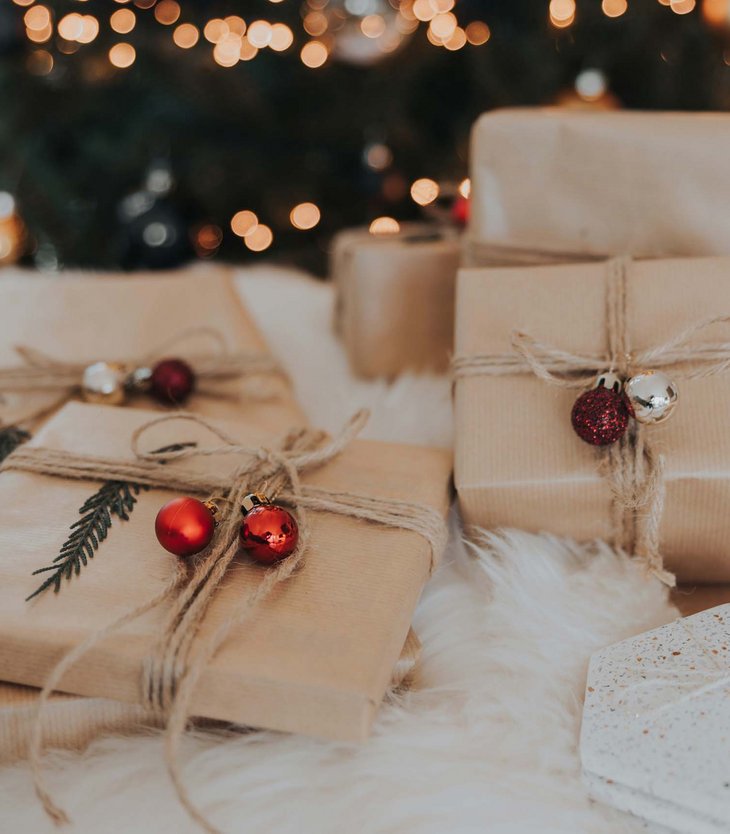 Ihr Hotel im Pustertal mit 5 Sternen: Alpen Tesitin Weihnachtsgeschenke in braunem Papier mit roten und silbernen Kugeln unter Baum