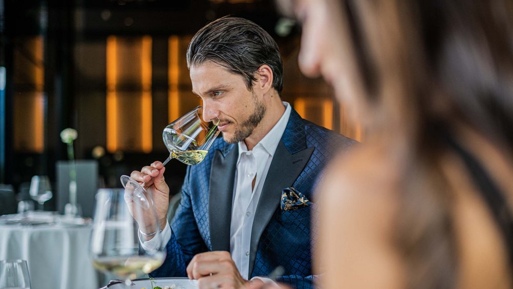 Le foto più belle dell’Alpen Tesitin Uomo in abito blu annusa vino bianco in ristorante elegante