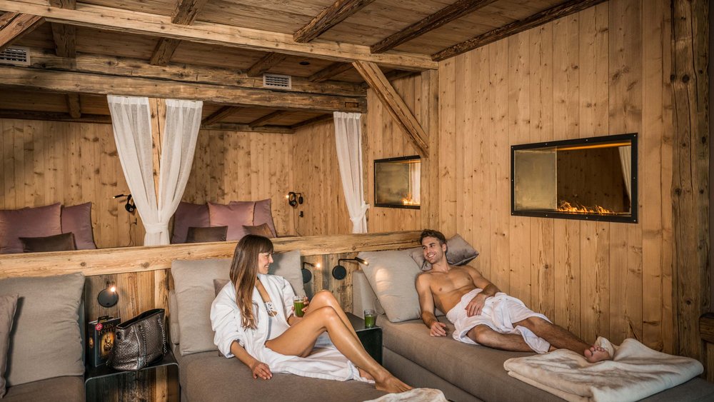 Le foto più belle dell’Alpen Tesitin Coppia che si rilassa in spa in legno con camino e lettini