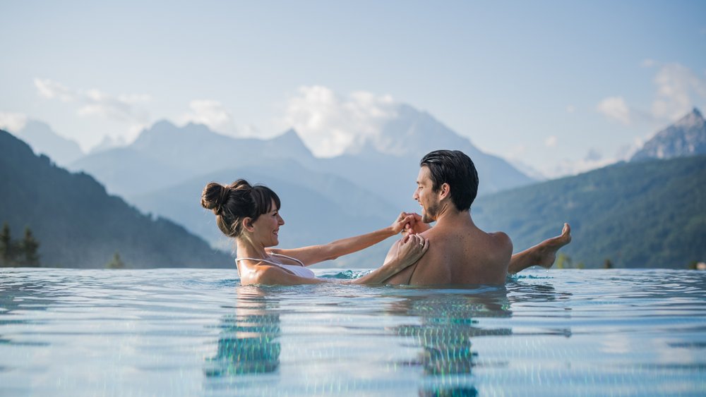 Le foto più belle dell’Alpen Tesitin Coppia che si rilassa in piscina a sfioro con vista sulle montagne