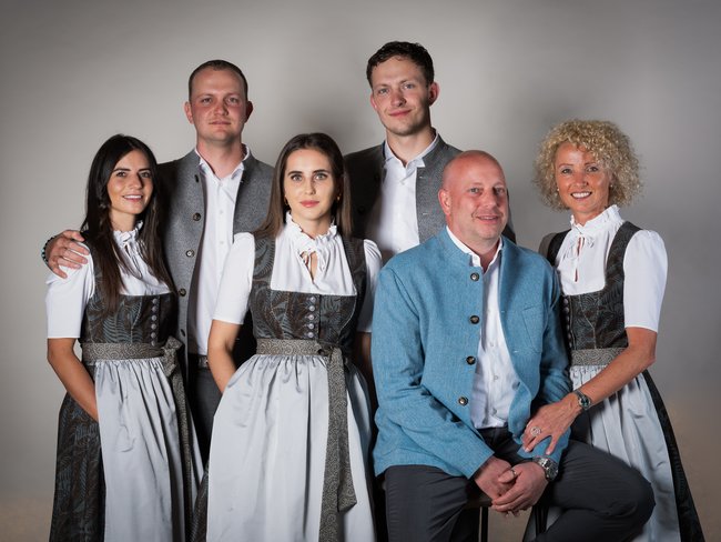 Ihr Hotel im Pustertal mit 5 Sternen: Alpen Tesitin Sechs Personen in traditionellen Trachten posieren vor neutralem Hintergrund