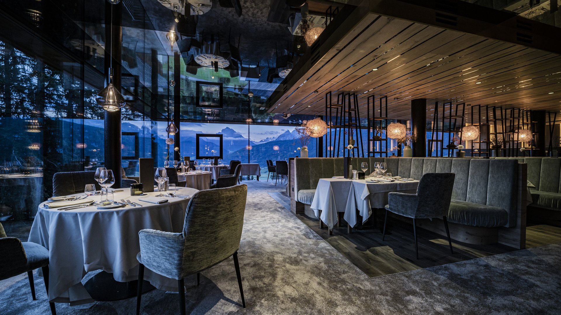 Alpen Tesitin: Ihr Hotel in den Dolomiten mit 5 Sternen Elegantes Restaurant mit Tischen, Stühlen und Bergblick bei Dämmerung