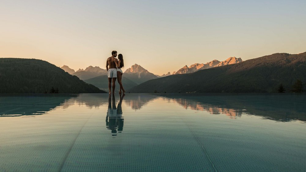 Le foto più belle dell’Alpen Tesitin Coppia in piscina a sfioro con vista sulle montagne al tramonto