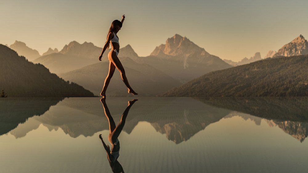 Le foto più belle dell’Alpen Tesitin Donna in costume da bagno cammina sull'acqua con montagne sullo sfondo
