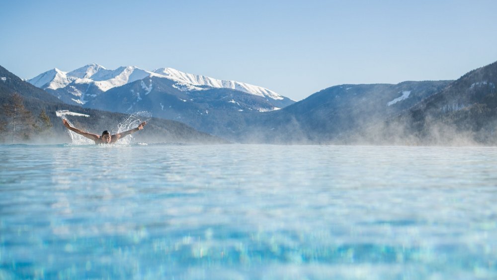 Le foto più belle dell’Alpen Tesitin Persona che nuota in piscina riscaldata con montagne innevate sullo sfondo