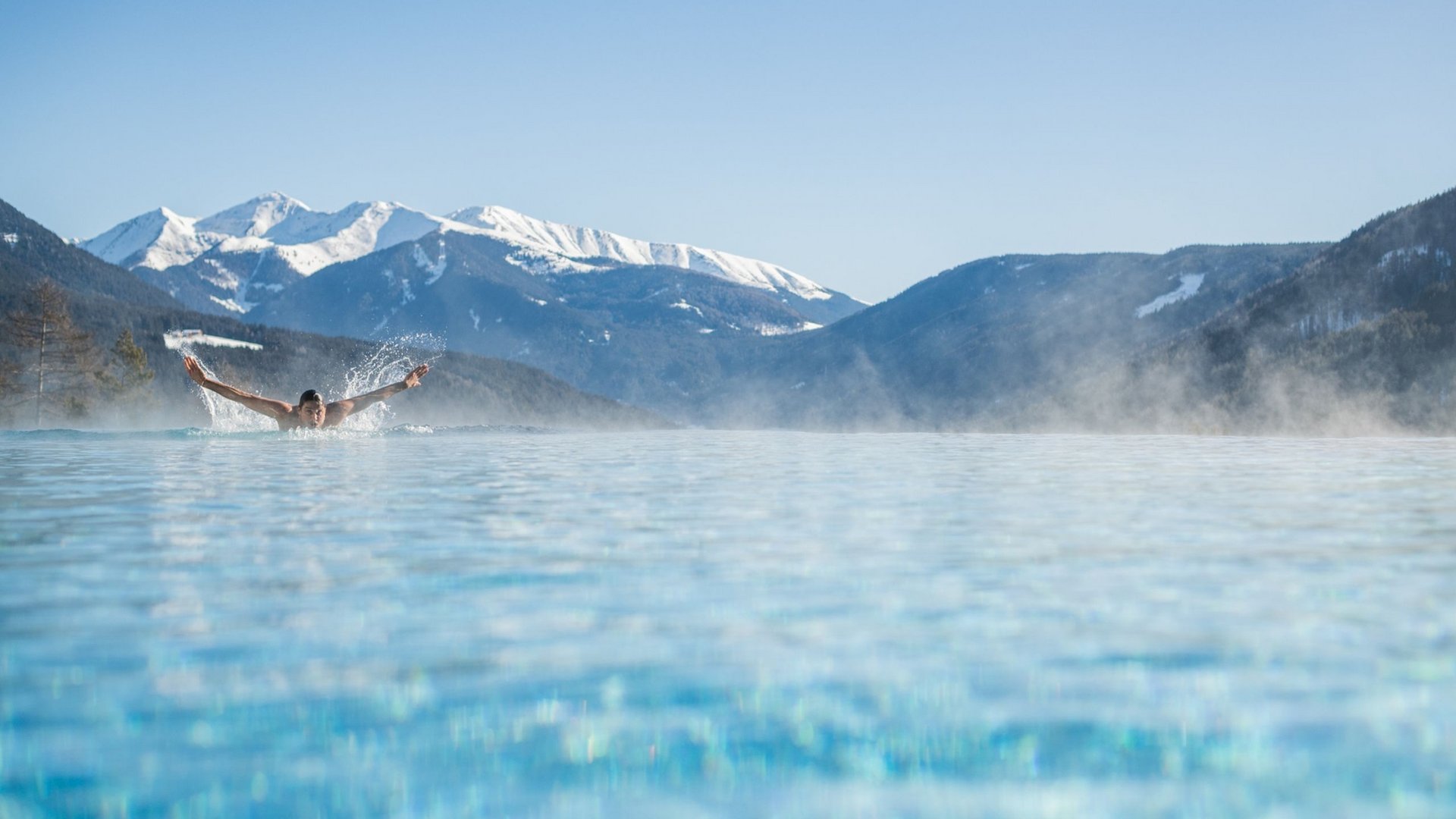 Ihr Hotel im Pustertal mit 5 Sternen: Alpen Tesitin Person schwimmt in beheiztem Pool vor verschneiten Bergen