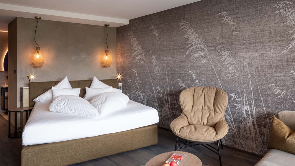 Le foto più belle dell’Alpen Tesitin Camera d'albergo moderna con letto matrimoniale, poltrona comoda e parete decorativa