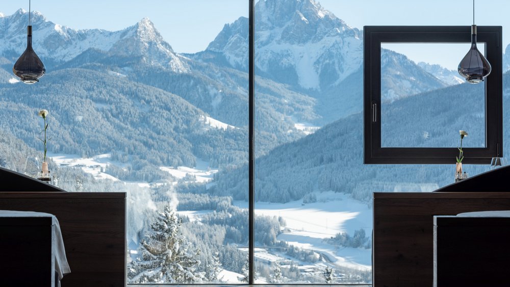 Le foto più belle dell’Alpen Tesitin Vista sulle montagne innevate attraverso una grande finestra in una stanza moderna
