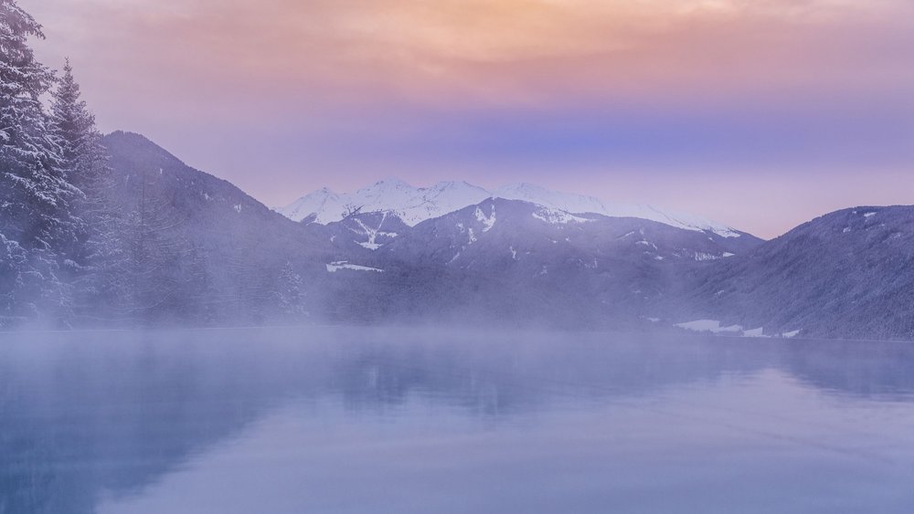 Pictures of our Alpen Tesitin Foggy mountain landscape with snow-covered peaks and calm water