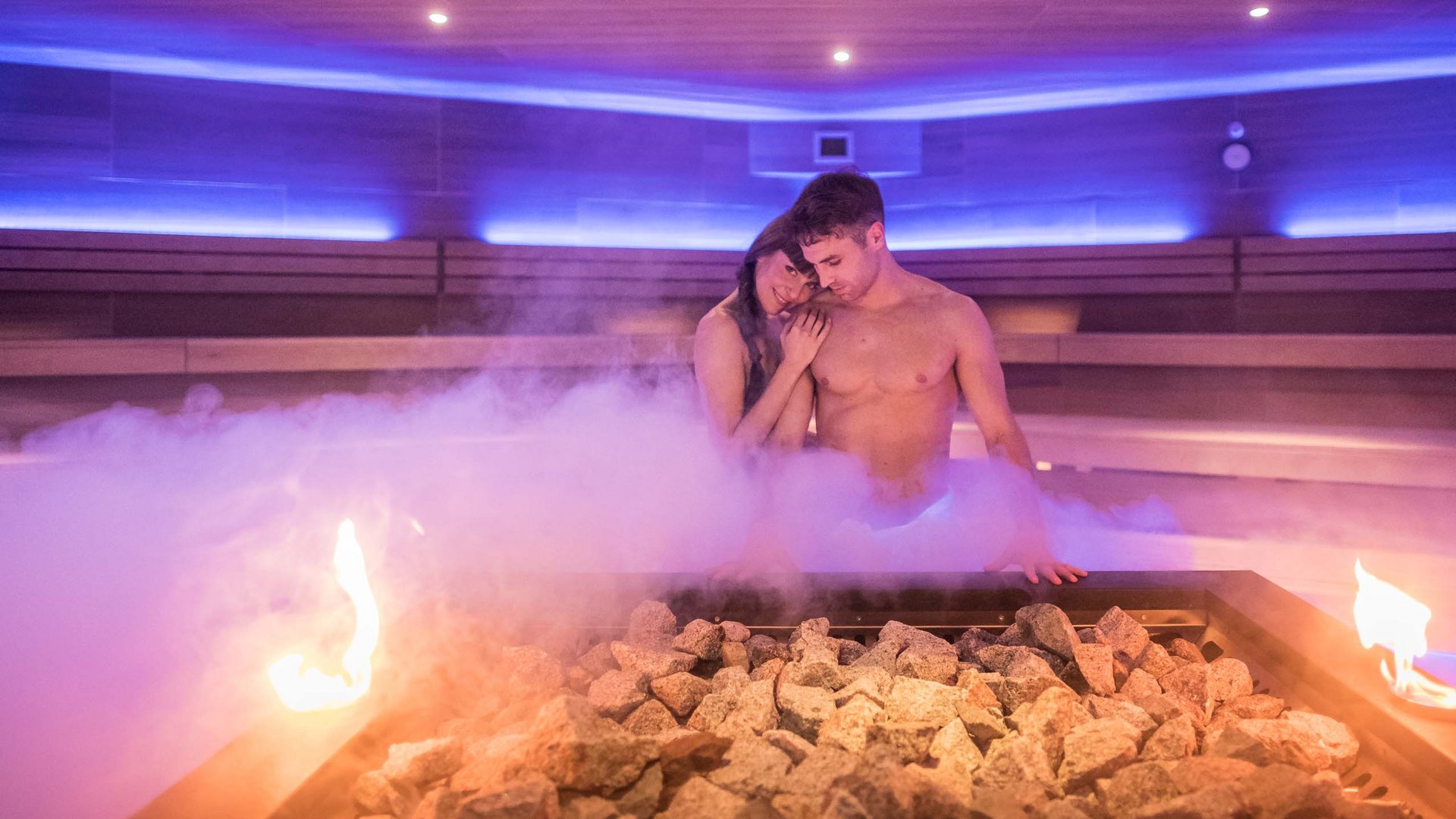 Ihr Hotel im Pustertal mit 5 Sternen: Alpen Tesitin Paar entspannt in einer dampfenden Sauna mit Feuer und Steinen