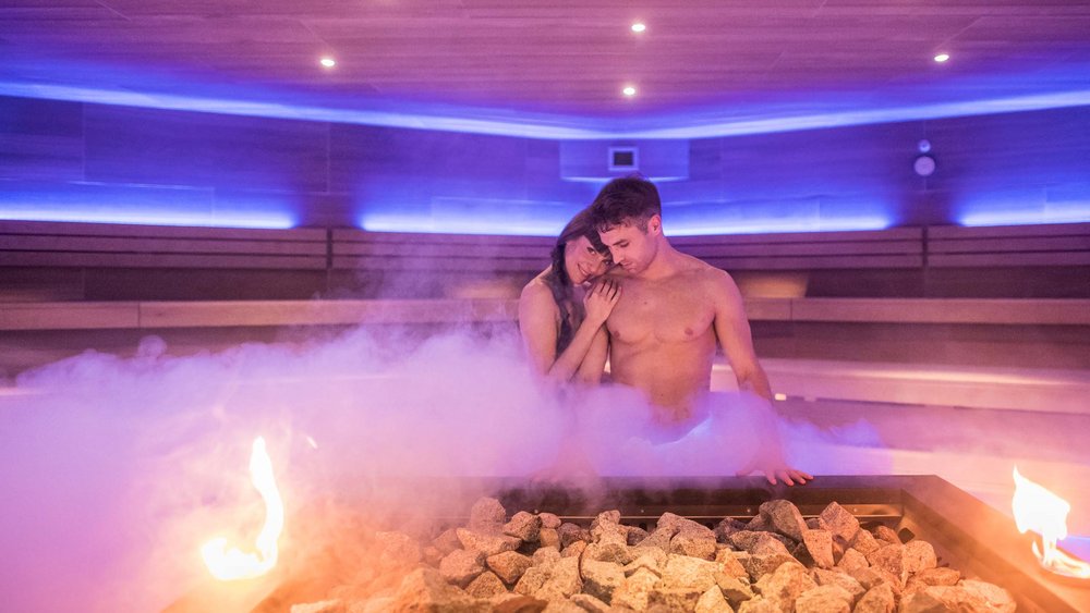 Le foto più belle dell’Alpen Tesitin Coppia che si rilassa in una sauna fumante con pietre e fuoco