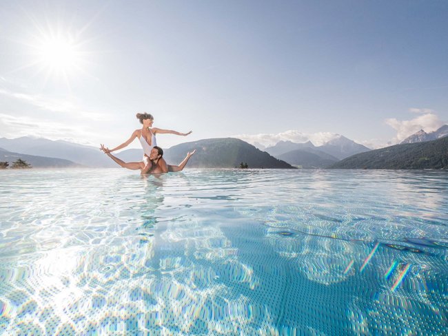 Your hotel in Val Pusteria/Pustertal with pool oasis Couple enjoying sunshine in a pool with mountain view