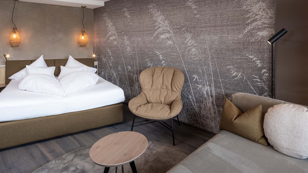 Pictures of our Alpen Tesitin Modern hotel room with double bed, armchair, and sofa against a wall with reed pattern