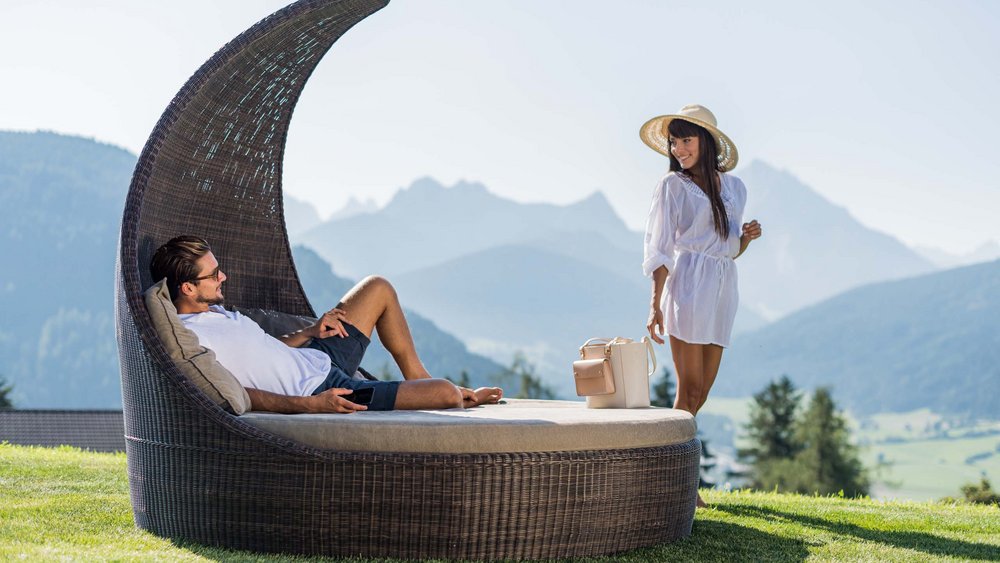 Le foto più belle dell’Alpen Tesitin Uomo sdraiato su lettino da giardino, donna con cappello da sole davanti a montagne