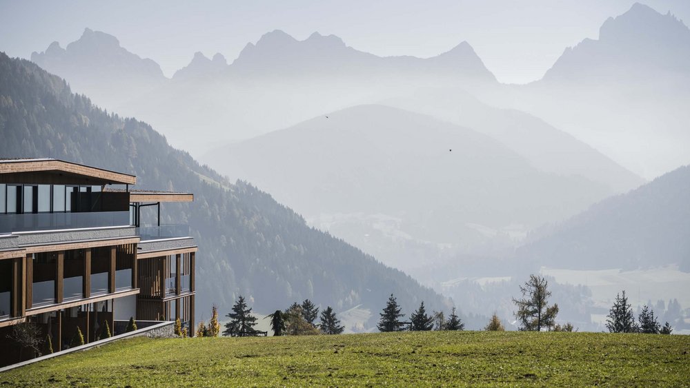Le foto più belle dell’Alpen Tesitin Edificio su collina verde con montagne nebbiose sullo sfondo
