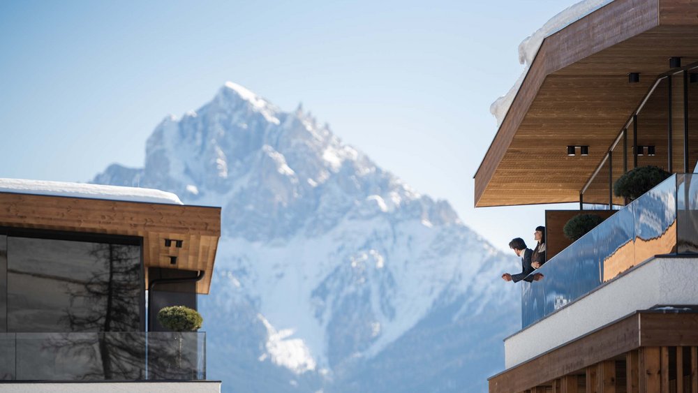 Le foto più belle dell’Alpen Tesitin Coppia guarda dalla balconata di un chalet moderno una montagna innevata