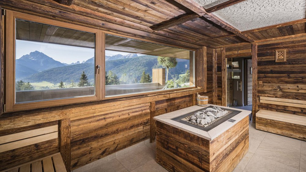 Le foto più belle dell’Alpen Tesitin Sala benessere rustica con forno sauna e vista sulle Alpi dalla finestra grande