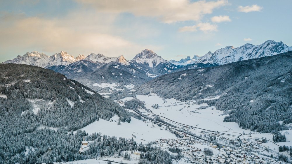 Le foto più belle dell’Alpen Tesitin Valle montano innevato con villaggio e colline boschive all'alba