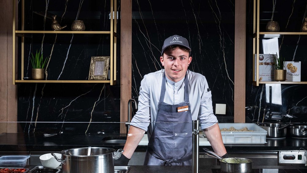 Le foto più belle dell’Alpen Tesitin Cuoco giovane in cucina professionale dietro il bancone con pentole