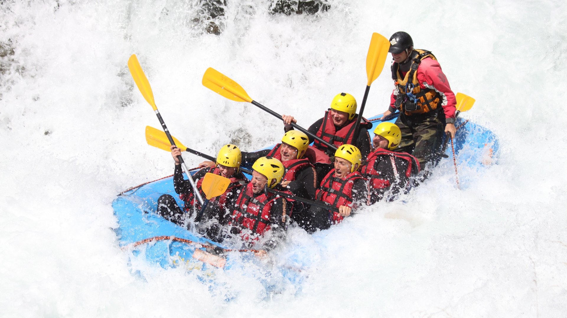 Action & adventure in Alta Pusteria/Hochpustertal Group whitewater rafting with yellow helmets and red life jackets on a blue raft