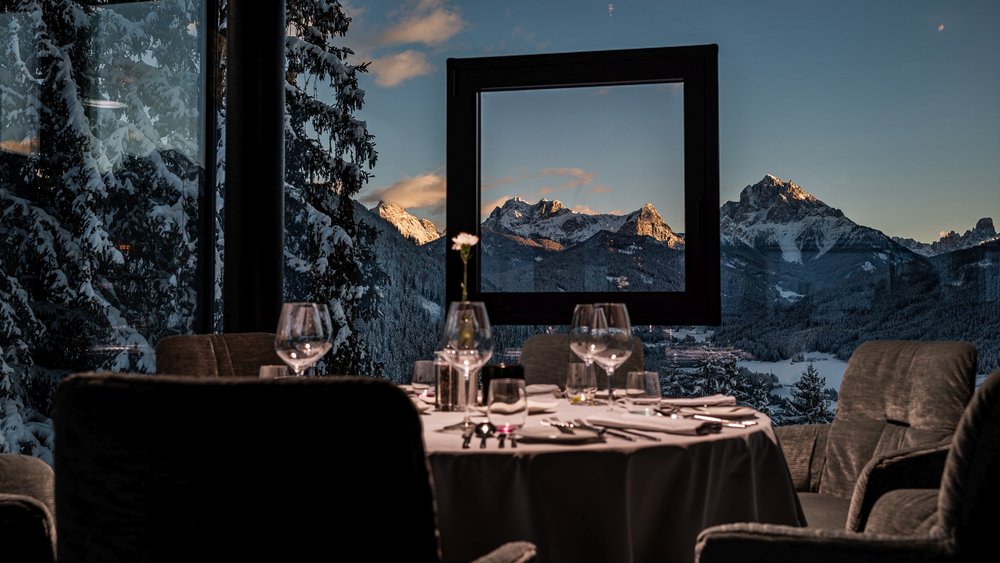 Le foto più belle dell’Alpen Tesitin Ristorante elegante con vista sulle montagne innevate attraverso una finestra aperta