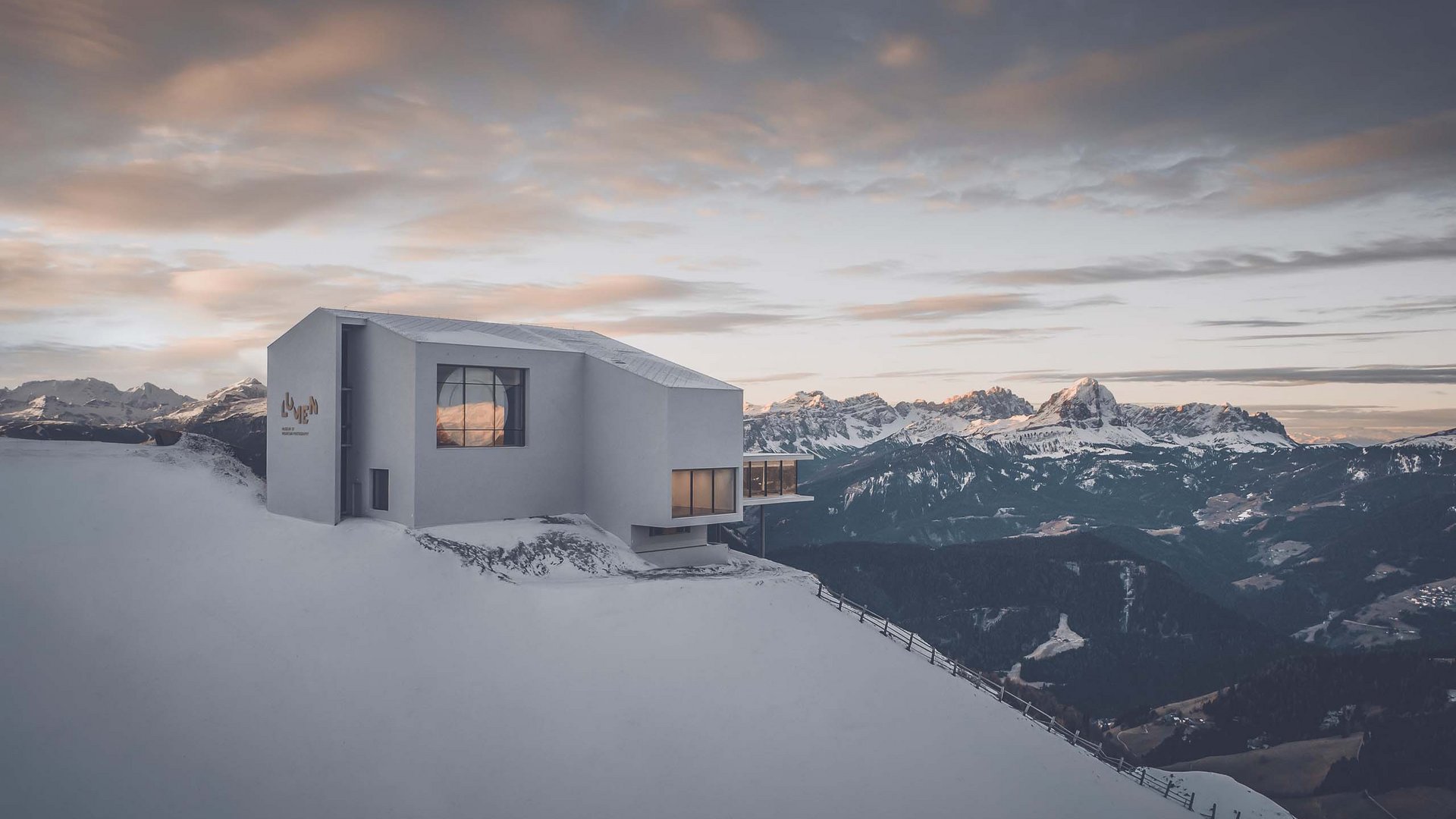 These attractions await you in Val Pusteria/Pustertal! Modern building on snowy mountain with alpine panorama in the background
