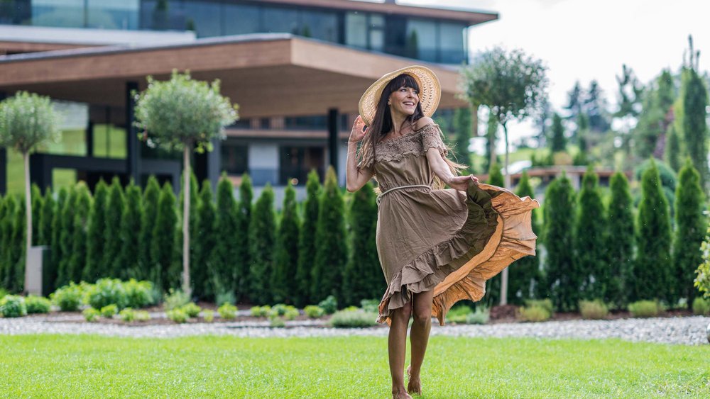 Le foto più belle dell’Alpen Tesitin Donna in abito e cappello che danza a piedi nudi sul prato davanti a casa moderna
