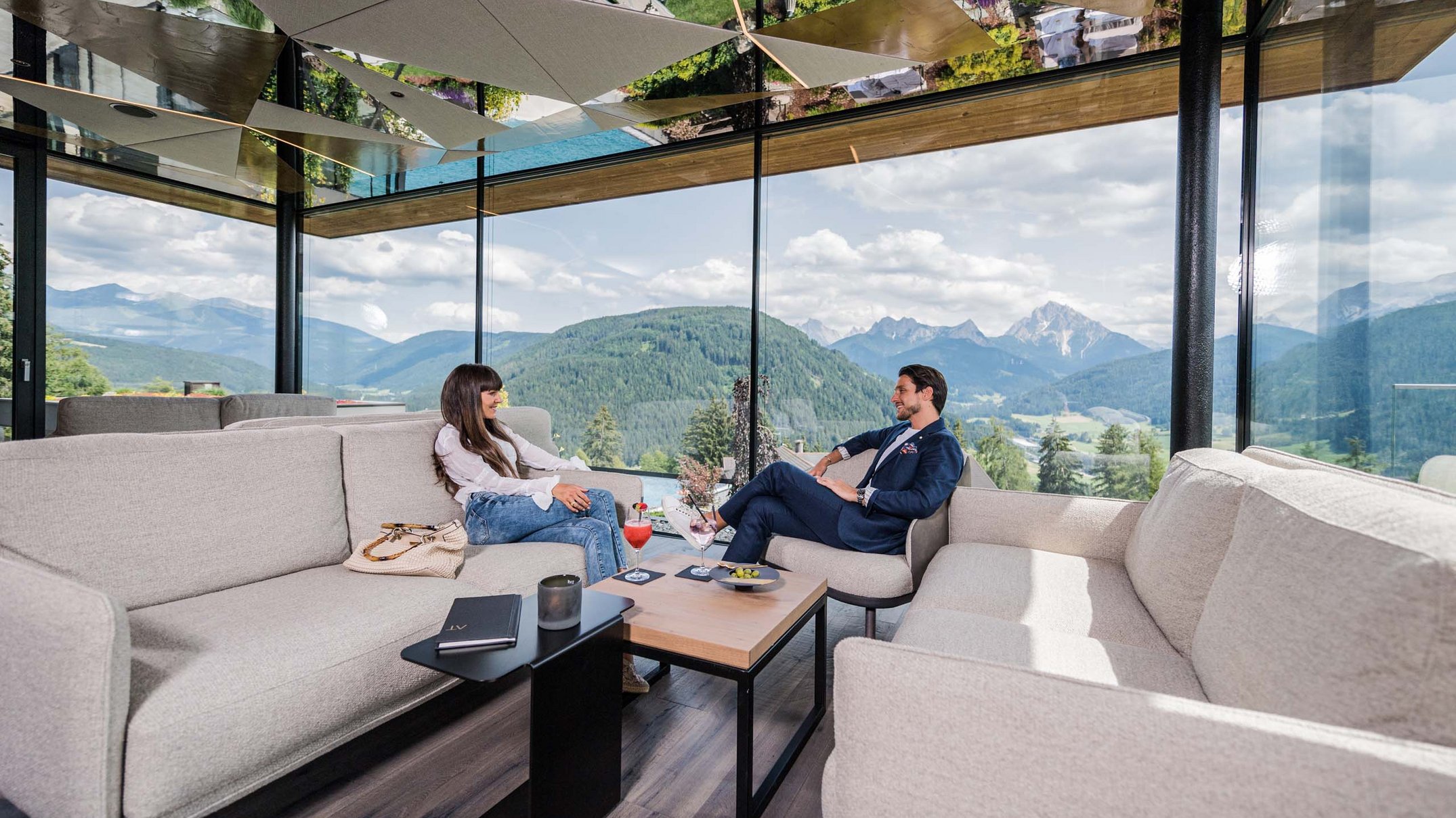 Ihr Hotel im Pustertal mit 5 Sternen: Alpen Tesitin Zwei Personen sitzen in modernem Wohnzimmer mit Panoramablick auf Berge