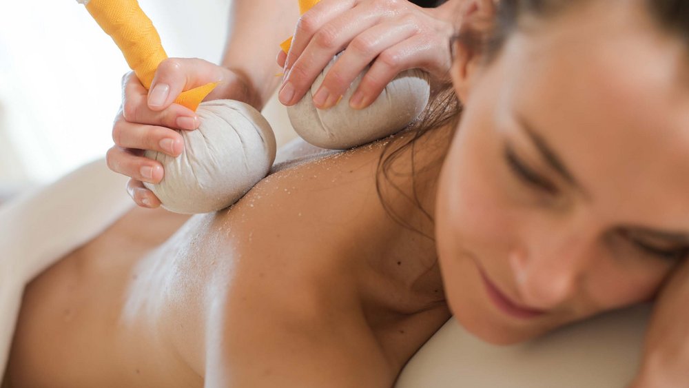 Le foto più belle dell’Alpen Tesitin Donna che riceve massaggio con sacchetti di erbe sulla schiena