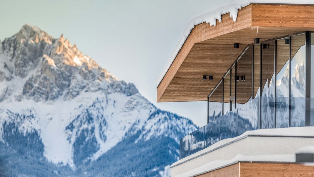 Le foto più belle dell’Alpen Tesitin Casa moderna con facciata in legno e balcone in vetro davanti a montagna innevata