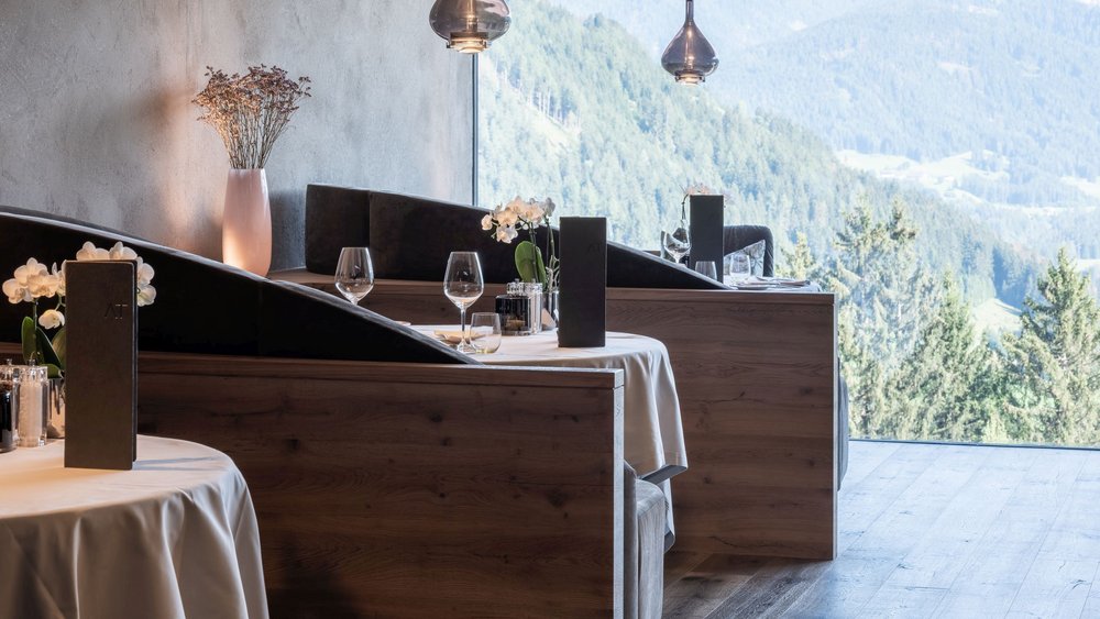 Le foto più belle dell’Alpen Tesitin Ristorante moderno con tavoli in legno e vista sulle montagne dalle grandi finestre