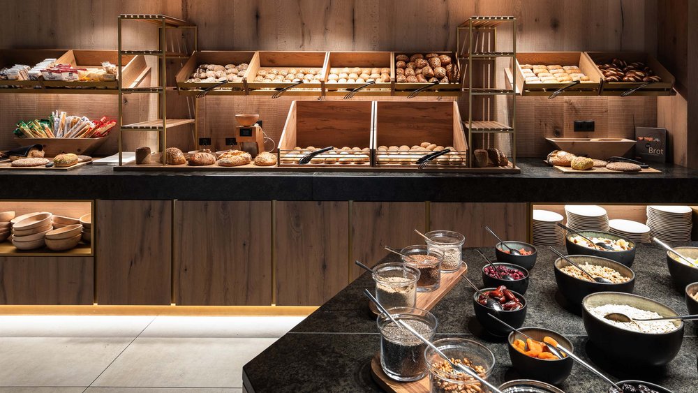 Le foto più belle dell’Alpen Tesitin Buffet con vari tipi di pane e cereali in ciotole in ambiente moderno