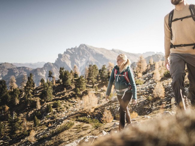 Alpen Tesitin, our hiking hotel in Val Pusteria/Pustertal Two people hiking in mountains with clear sky and autumn landscape