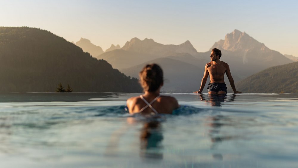 Le foto più belle dell’Alpen Tesitin Due persone in una piscina a sfioro con vista sulle montagne al tramonto
