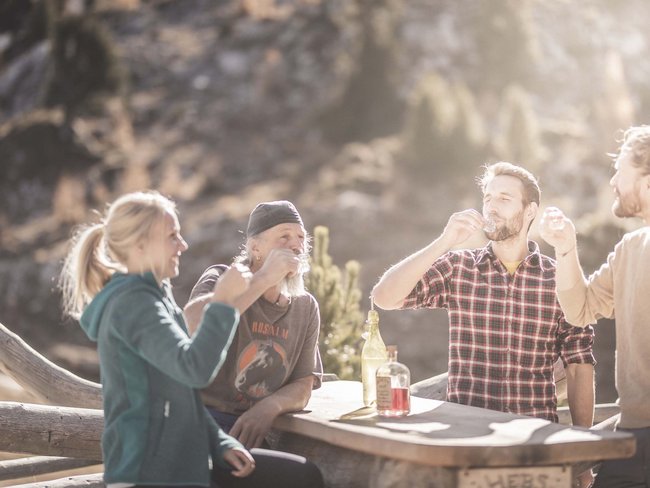 Alpen Tesitin, our hiking hotel in Val Pusteria/Pustertal Four people enjoying drinks outdoors in sunlight