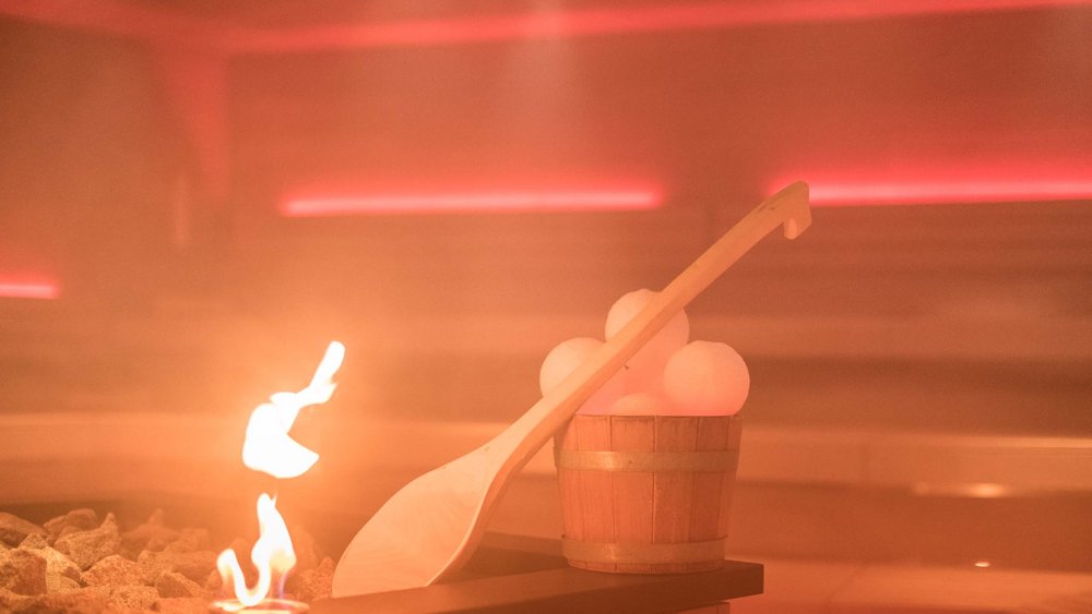 Le foto più belle dell’Alpen Tesitin Stufa della sauna con fiamma e secchio di legno con pietre di sale nella stanza a vapore