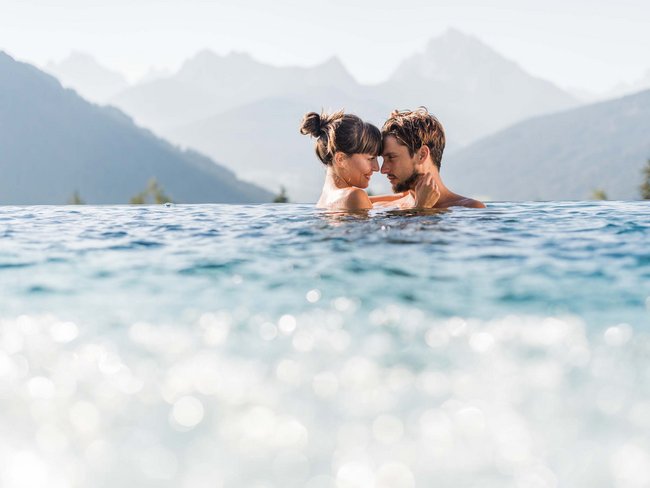 Your hotel in Val Pusteria/Pustertal with pool oasis Couple enjoying infinity pool with mountain views