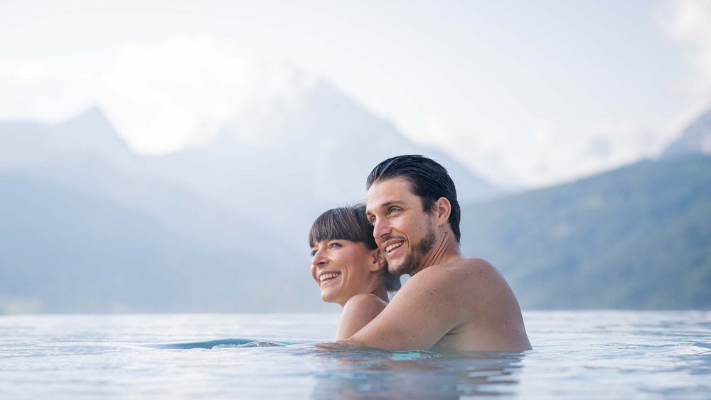 Le foto più belle dell’Alpen Tesitin Coppia che si abbraccia in piscina con paesaggio montano sullo sfondo