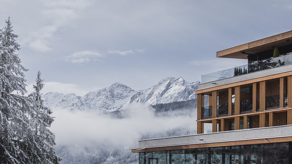 Le foto più belle dell’Alpen Tesitin Edificio moderno davanti a montagne innevate e bosco con nebbia