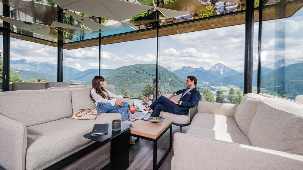 Le foto più belle dell’Alpen Tesitin Due persone sedute in una stanza moderna con vista panoramica sulle montagne