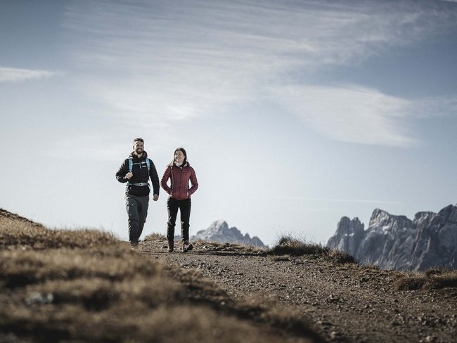 Alpen Tesitin, our hiking hotel in Val Pusteria/Pustertal Couple hiking on mountain trail with mountain landscape in background